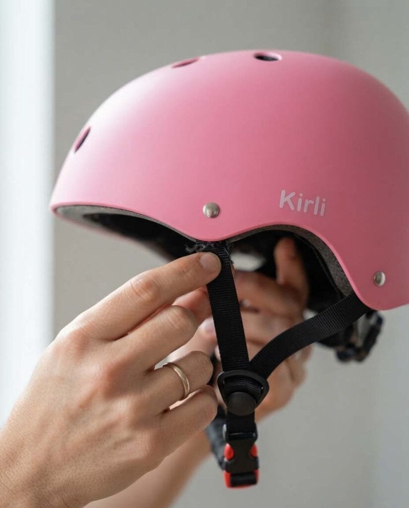 Parent checking the chin strap rivets on a child's bicycle helmet